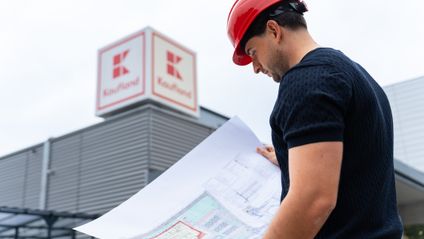 Architekt z oddelenia expanzie číta plán novej predajne pred obchodom