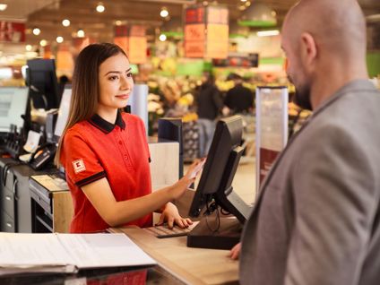 Kaufland-Verkaufsmitarbeiterin im Gespräch mit einem Kunden an der Informationstheke.
