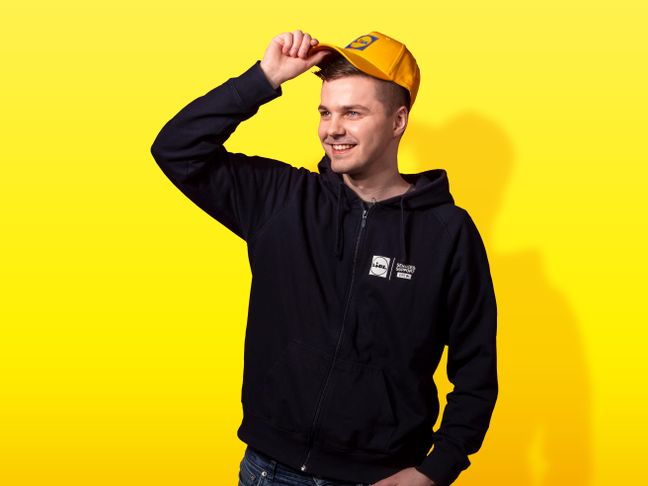 IT-työntekijä hymyilee lippis päässä.