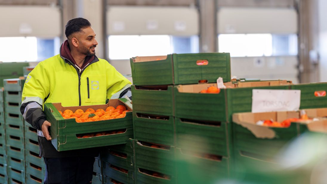 Lagermedarbejdere med appelsiner i hånden