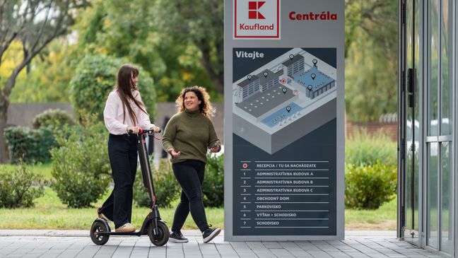 Študentka a brigádnička na kolobežke pred vchodom do centrály