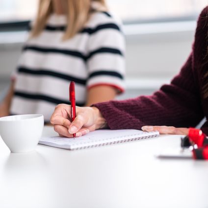 administratívna pracovníčka v office si píše poznámky perom do zošita