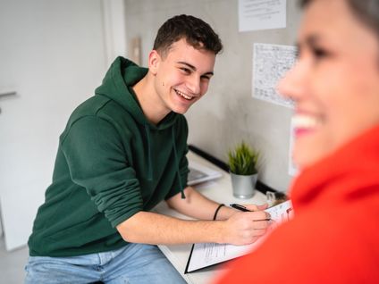 Mutter und Sohn machen sich Notizen am Schreibtisch für eine Bewerbung
