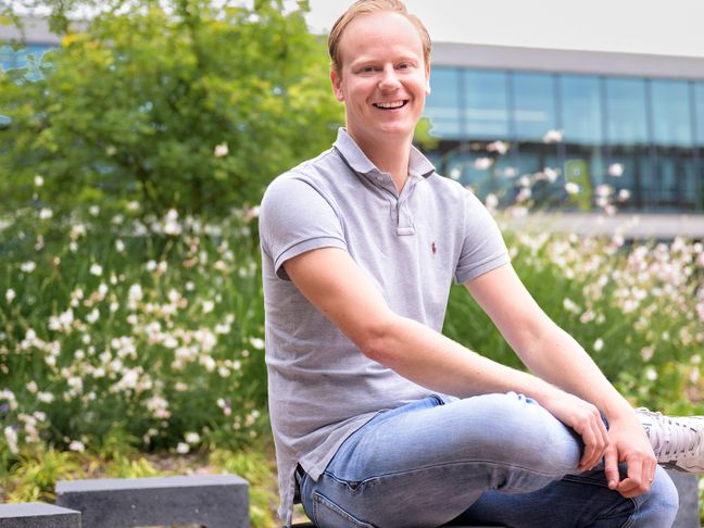 IT collega Stefan zit op bankje in de Lidl campus tuin