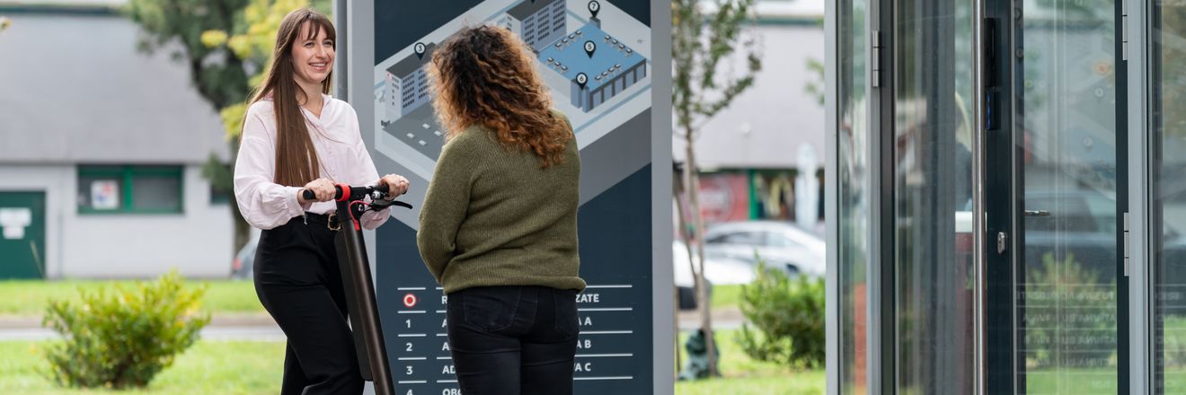 Brigádnička a trainee na kolobežke pred vchodom centrály