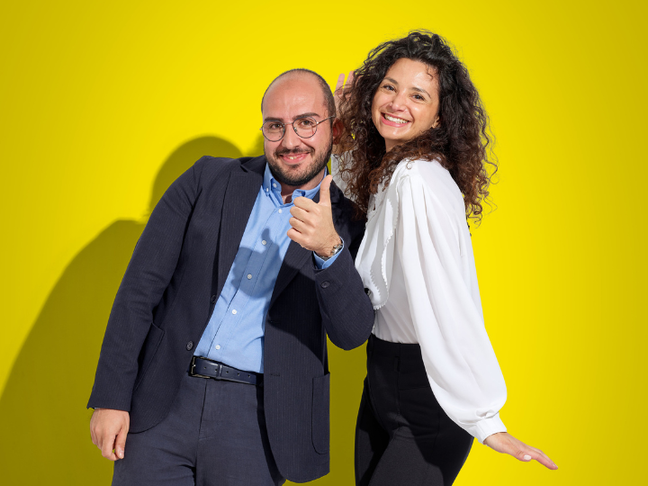 donna e uomo in abbigliamento d'ufficio sorridono e scherzano in camera