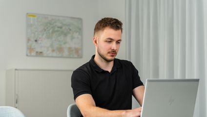 Trainee z oddelenia controllingu v office pracuje na notebooku