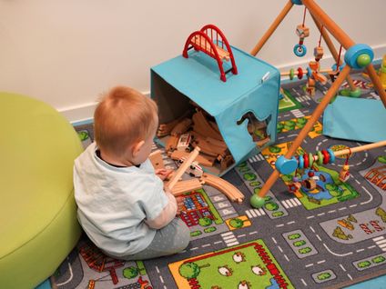 Kind spielt im Eltern-Kind-Büro mit Holzspielzeug.
