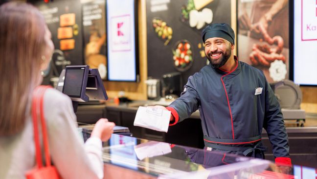 An der Bedientheke einer Kaufland-Filiale: Mitarbeiter in der Fleisch- und Wurstabteilung überreicht der Kundin ihre Bestellung.