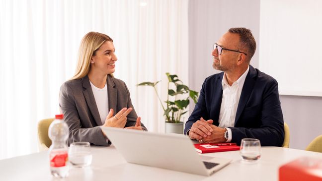 Kandidatin mit Kaufland-Mitarbeiter in einem Konferenzraum der Zentrale beim Bewerbungsgespräch. Auf dem Tisch steht ein aufgeklappter Laptop.