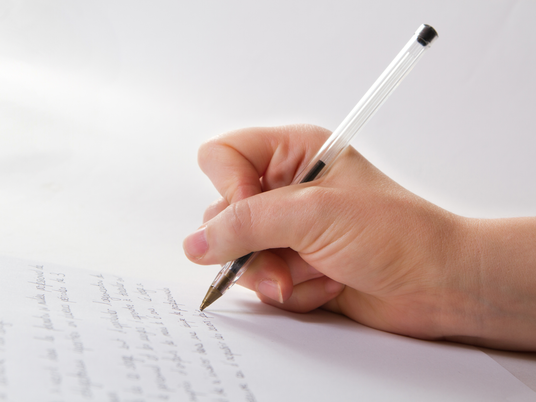 Persona ha in mano una penna e scrive su un foglio