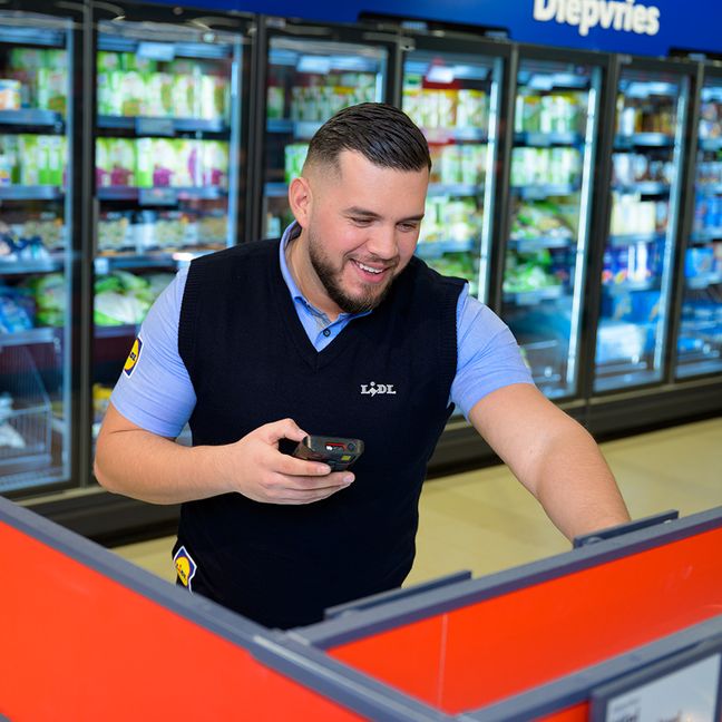 Plaatsvervangend supermarktmanager van Lidl gebruikt een handscanner.