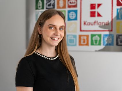 Asistentka z oddelenia nákupu stojí v office pred obrazom Kaufland.