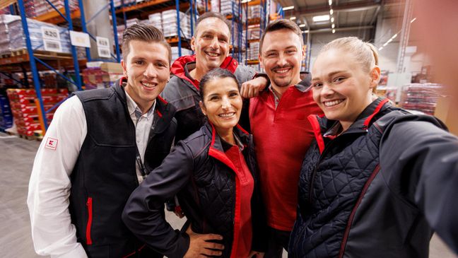Gruppen-Selfie: Fünf Logistikmitarbeiter von Kaufland posieren vor der Handykamera.
