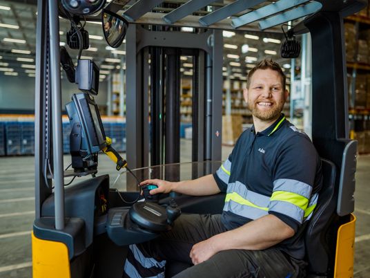 Varastotyöntekijä ajaa trukilla ja nauraa