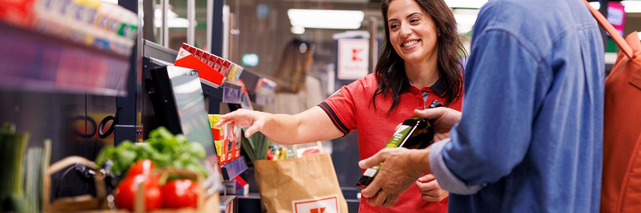Kaufland-Verkaufsmitarbeiterin hilft einem Kunden an der SB-Kasse.