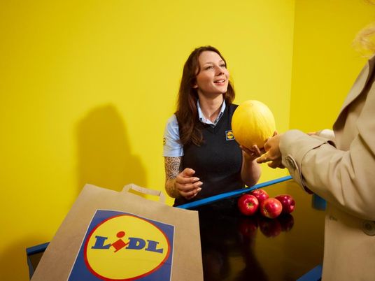 Mitarbeiterin kassiert Obst und Gemüse