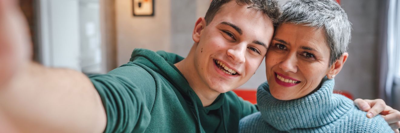 Mutter und Sohn machen ein Selfie und lächeln freundlich in die Kamera