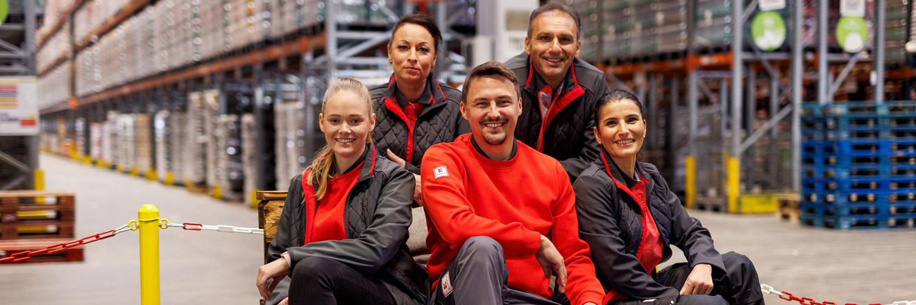 Fünf Logistikmitarbeiter von Kaufland haben zum Gruppenfoto auf einer Palette Platz genommen.