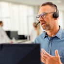 Kaufland-Mitarbeiter mit Headset vor einem Bildschirm in angeregtem Gespräch bei einer Telko.
