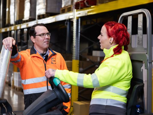 Varastotyöntekijät kuljettavat Lidlin kylttiä