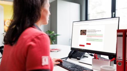 Kaufland-Verkaufsmitarbeiterin am Schreibtisch mit Tastatur und Bildschirm.