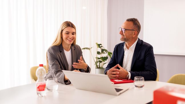 Kandidatin mit Kaufland-Mitarbeiter in einem Konferenzraum der Zentrale beim Bewerbungsgespräch. Auf dem Tisch steht ein aufgeklappter Laptop.