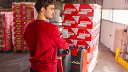 Logistikmitarbeiter von Kaufland rangiert mit einem Hubwagen Palettenware.