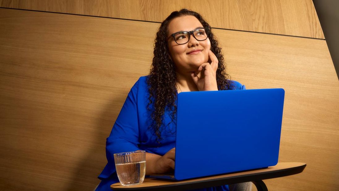 Mitarbeiterin sitzt vor einem Laptop und überlegt