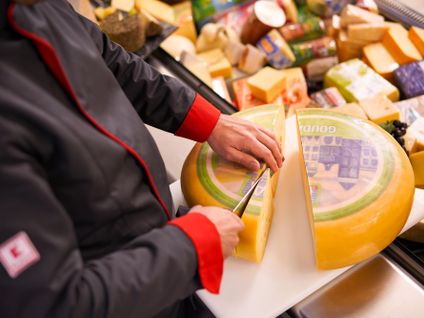 Kaufland-Bedientheke: Ein Verkaufsmitarbeiter schneidet einen Laib Käse auf.