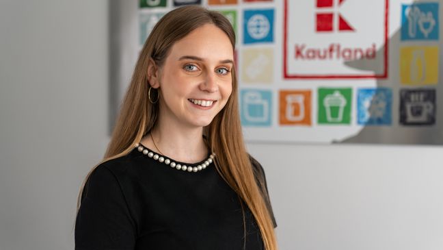 Asistentka z oddelenia nákupu stojí v office pred obrazom Kaufland.