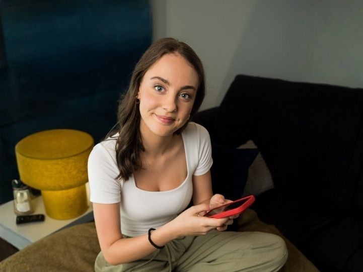 Lehrling zuhause mit Handy in der Hand