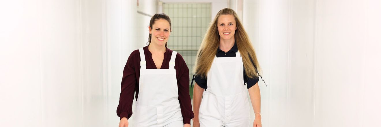 Zwei Kolleginnen aus dem Fleischwerk bei Kaufland laufen einen Gang entlang.