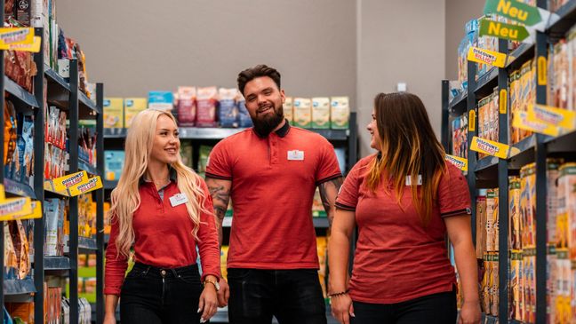 Drei Azubis laufen durch den Gang einer Kaufland-Filiale.