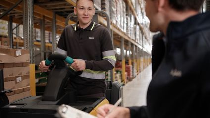 Teamleiter im Gespräch mit Staplerfahrer im Warenlager