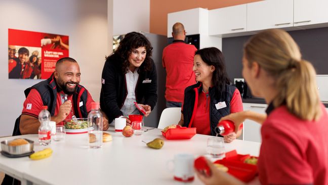 Vier Verkaufsmitarbeiter von Kaufland gut gelaunt bei der Mittagspause im Pausenraum der Filiale.