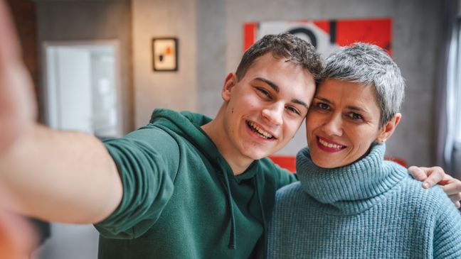 Mutter und Sohn machen ein Selfie und lächeln freundlich in die Kamera