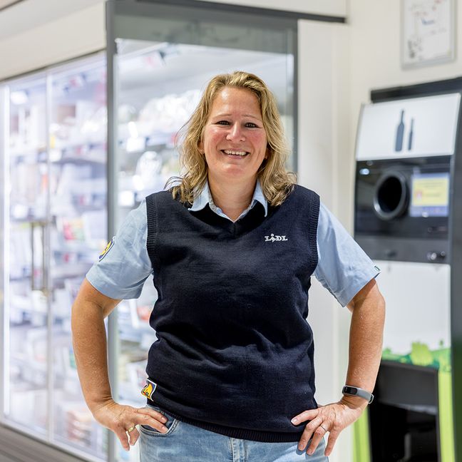 Glimlachende Lidl supermarktmanager voor een flessenautomaat
