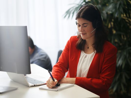 Mitarbeiterin arbeitet mit Headset am Computer