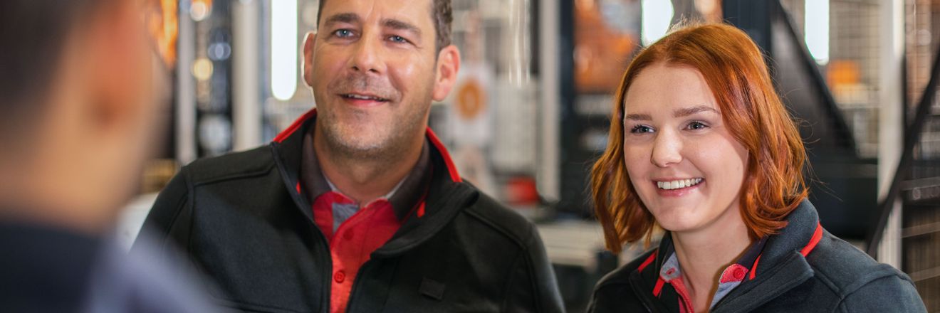 Zwei Logistik-Mitarbeiter von Kaufland unterhalten sich mit einem Kollegen.