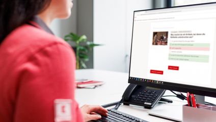 Kaufland-Verkaufsmitarbeiterin am Schreibtisch mit Tastatur und Bildschirm.