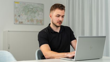 Trainee z oddelenia controllingu v office pracuje na notebooku