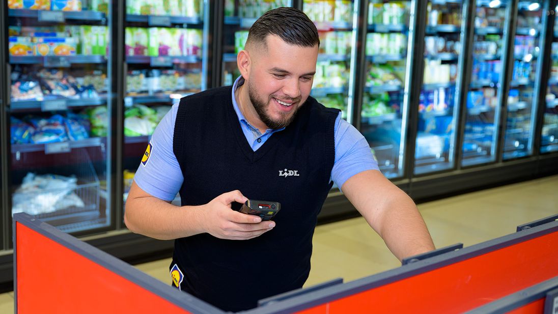 Plaatsvervangend supermarktmanager van Lidl gebruikt een handscanner.