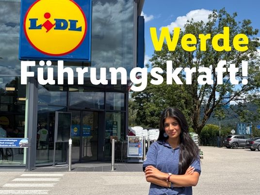 Lehrling steht vor der Filiale