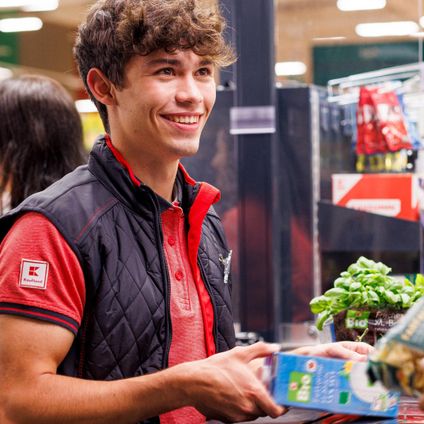 An der Kasse in einer Kaufland-Filiale: Junger Mitarbeiter kassiert den Einkauf einer Kundin.