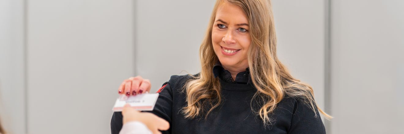 Pracovníčka recepcie odovzdáva kartičku návšteve centrály