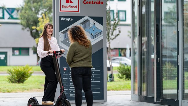 Brigádnička a trainee na kolobežke pred vchodom centrály