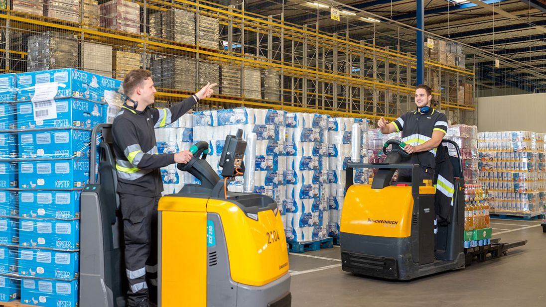 Orderpickers overleggen op elektrische pompwagens in een Lidl distributiecentrum.