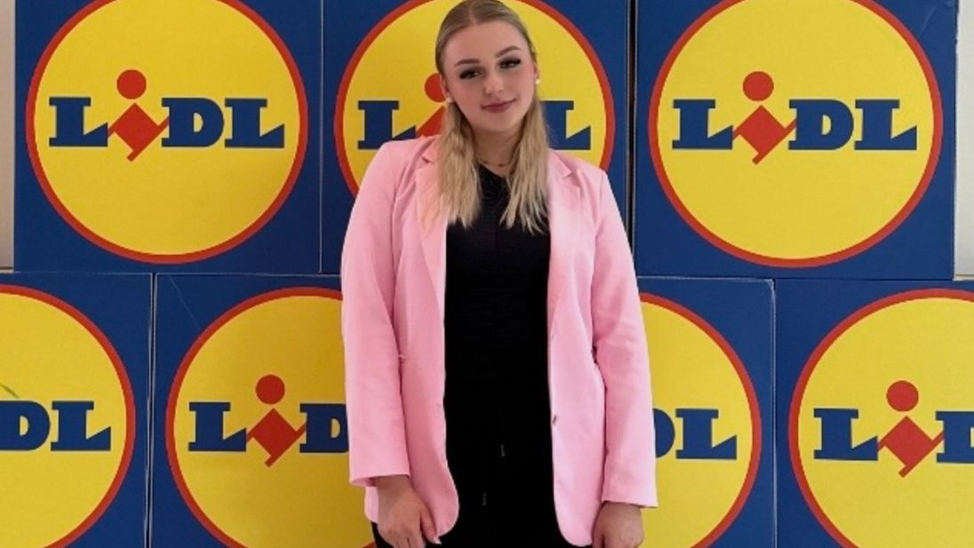 Azubine Elisabeth vor einer Wand mit Lidl Logos