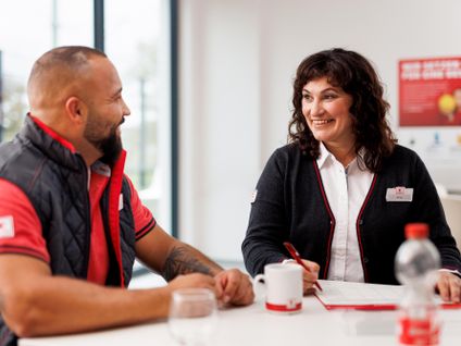 Verkaufsmitarbeiterin von Kaufland unterhält sich mit einem Kollegen im Pausenraum der Filiale.